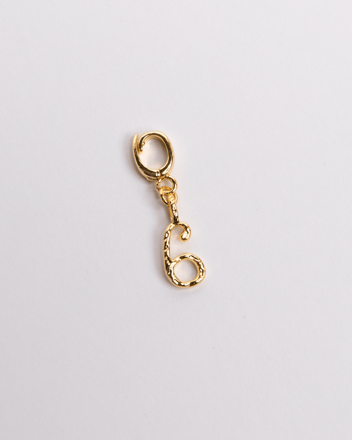 A gold-colored charm in the shape of a number six with a clasp, isolated on a white background.