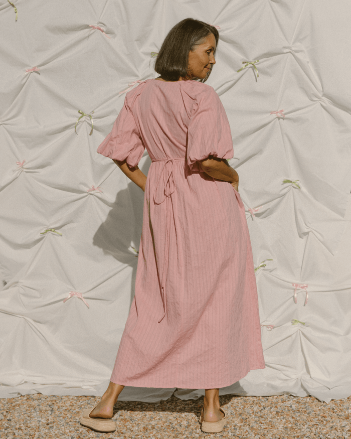 Woman wearing blush pink bump friendly wrap maxi dress.