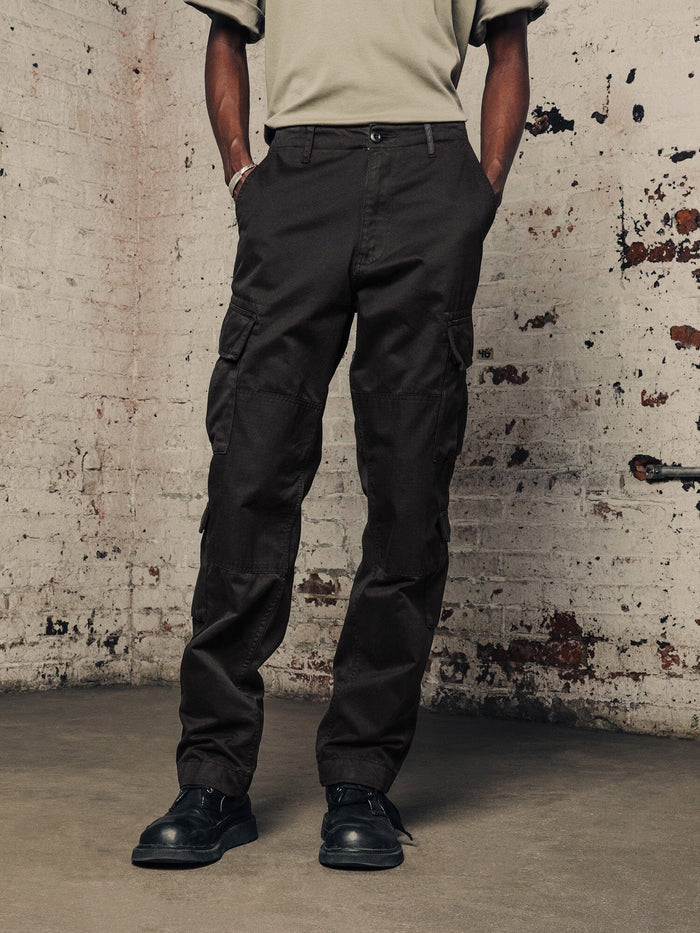 Alpha Industries Acu Pant cargo pants with utility pockets, beige shirt, black shoes.