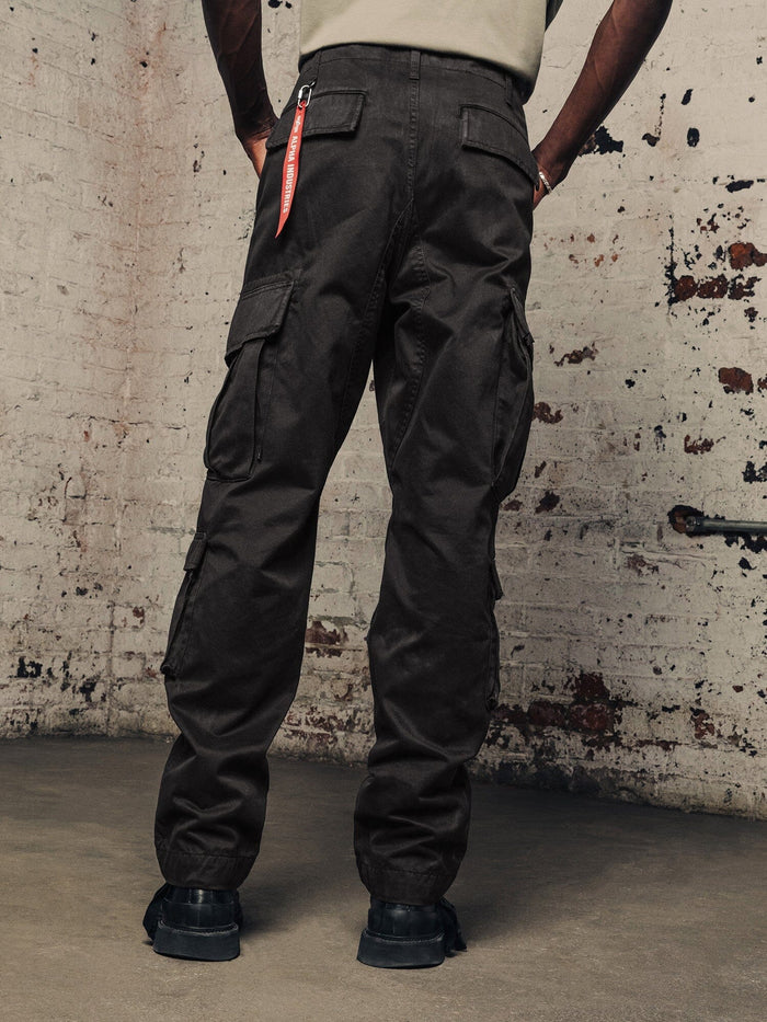 Alpha Industries Acu Pant cargo pants in dark color with multiple pockets, paired with black boots.
