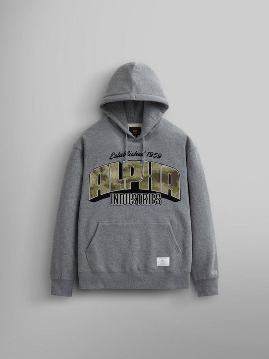 The Alpha Camo Logo Hoodie by Alpha Industries in charcoal heather. This unisex hoodie features the Alpha Industries camo logo prominently on the front with "Estab. Since 1959" above it. Crafted from heavy cotton, it includes a front pocket and a small label at the hem.