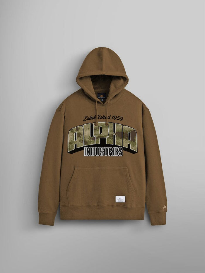 The Alpha Camo Logo Hoodie by Alpha Industries, showcases the brand name prominently on the front. Made from durable heavy cotton in a coyote brown color, it includes a front pocket and a small label at the bottom.