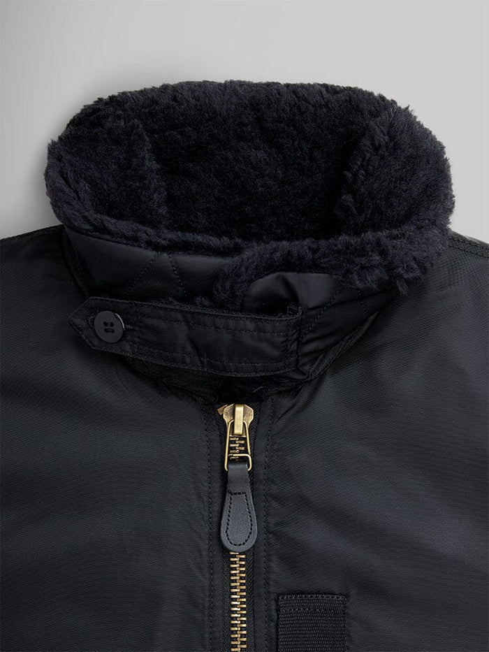 Alpha Industries B-15 Mod Bomber Jacket with black zippered front, buttoned collar strap, and dark faux mouton collar lining.