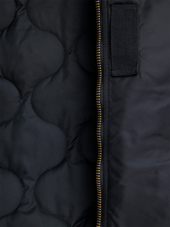 Alpha Industries B-15 Mod Bomber Jacket with black quilted fabric, gold vertical zipper, and black rectangular patch.