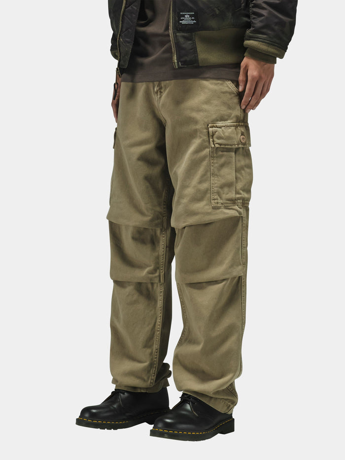 Alpha Industries Bdu Cargo Pant with side pockets, dark jacket, and black shoes; military-inspired design features.