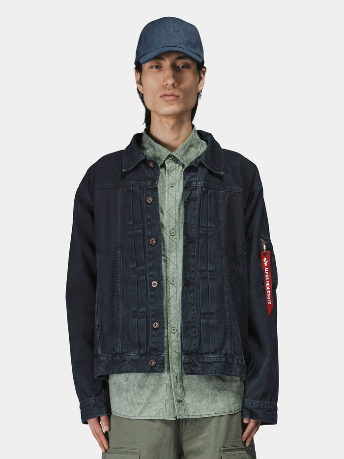 Alpha Industries Ctn Work Overshirt in dark fabric, layered over a light green button-up shirt with green pants and a blue cap.
