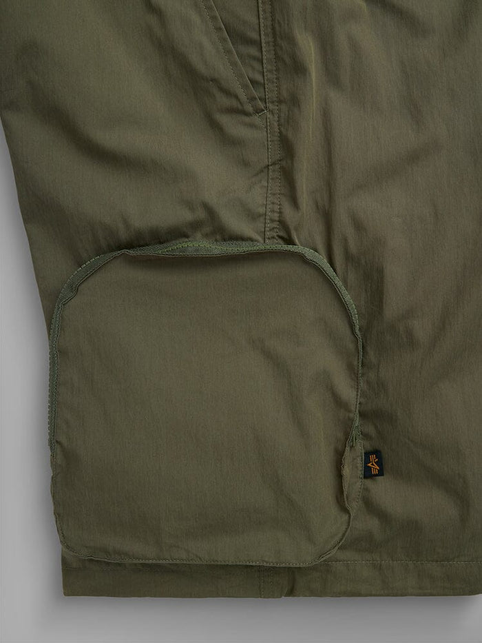 Alpha Industries Cwu 36/P Pull On Short in olive green with large rounded cargo pocket flap and small black tag with yellow logo on lower right side.