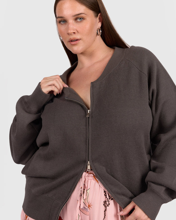 Woman wearing knit bomber in charcoal colour with two way breastfeeding access zips.
