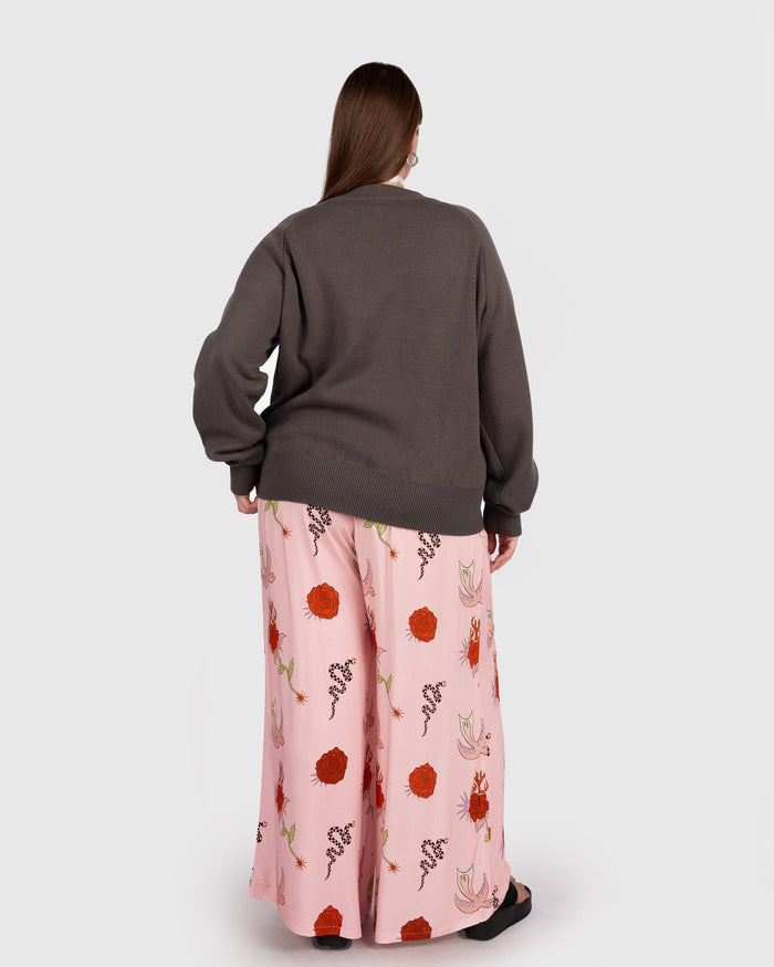 Person wearing a gray sweater and pink floral skirt on a white background