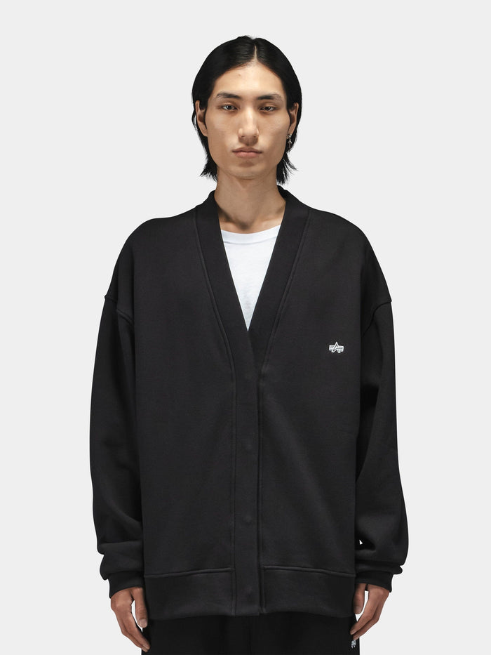 Alpha Industries Essential Cardigan in black with hidden snap closure, worn over a white t-shirt.