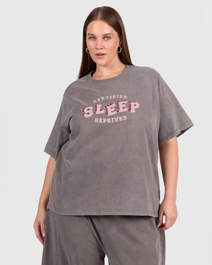 Person wearing a gray oversized t-shirt with 'Certified Sleep Deprived' text on a white background