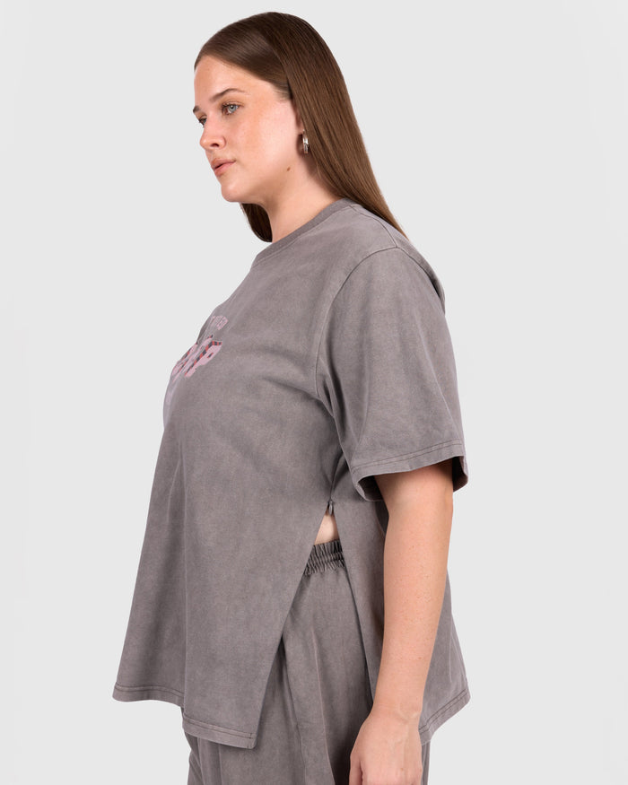 Woman wearing a gray t-shirt and pants on a plain background