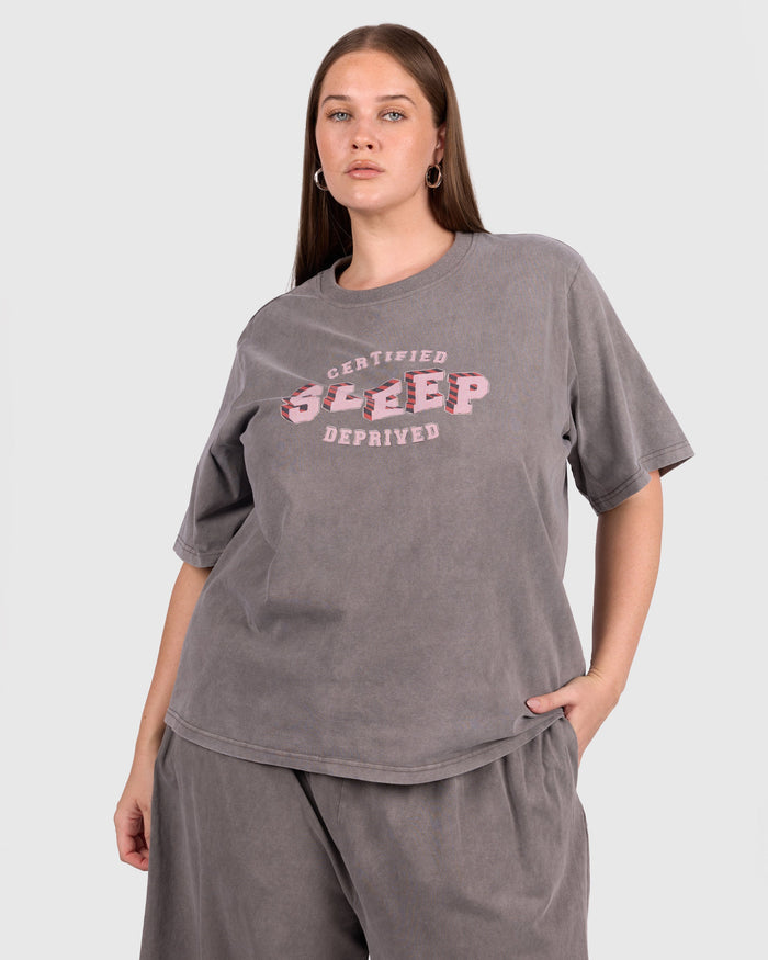 Woman wearing a gray oversized t-shirt with pink text on a white background