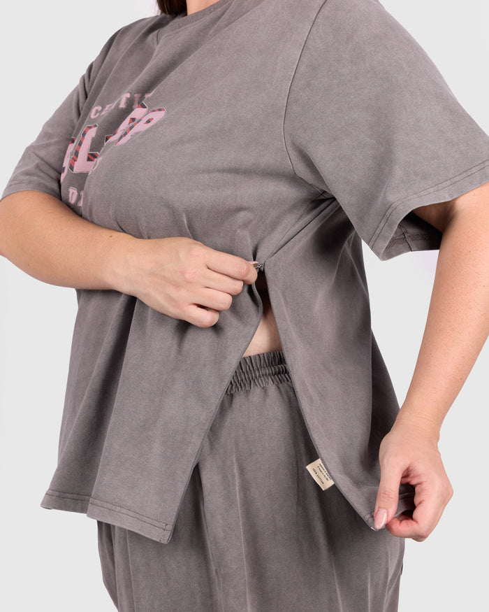 Person wearing a gray oversized t-shirt and shorts set on a light gray background