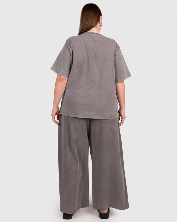 Woman wearing a gray outfit with wide-leg pants on a white background