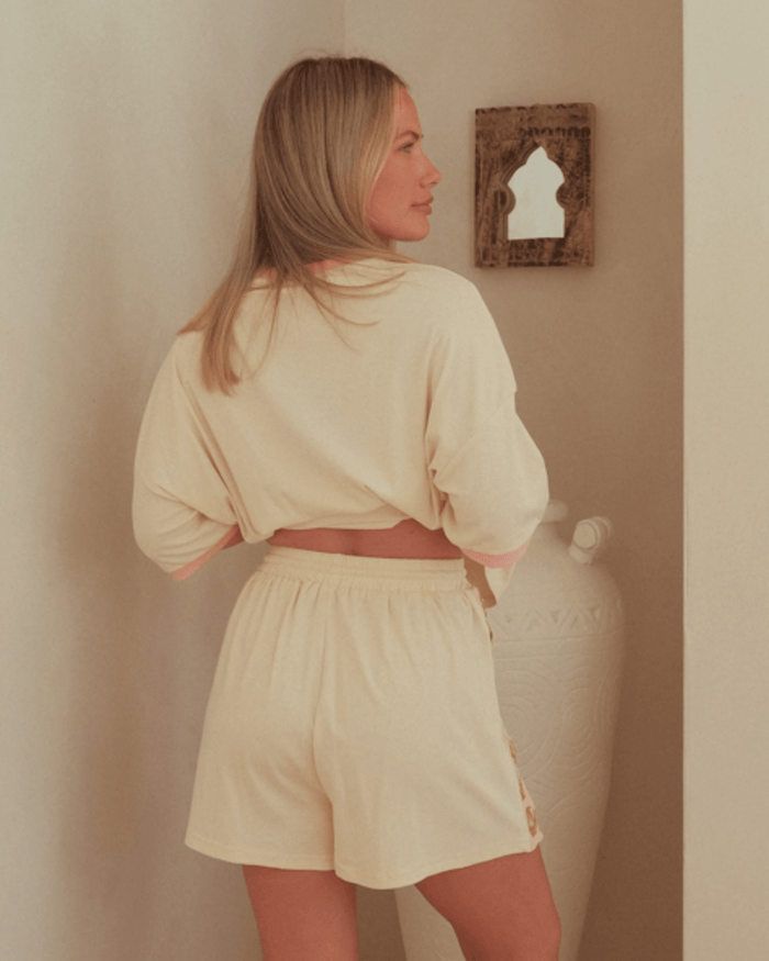 Woman wearing beige lounge shorts with elasticated waist band.