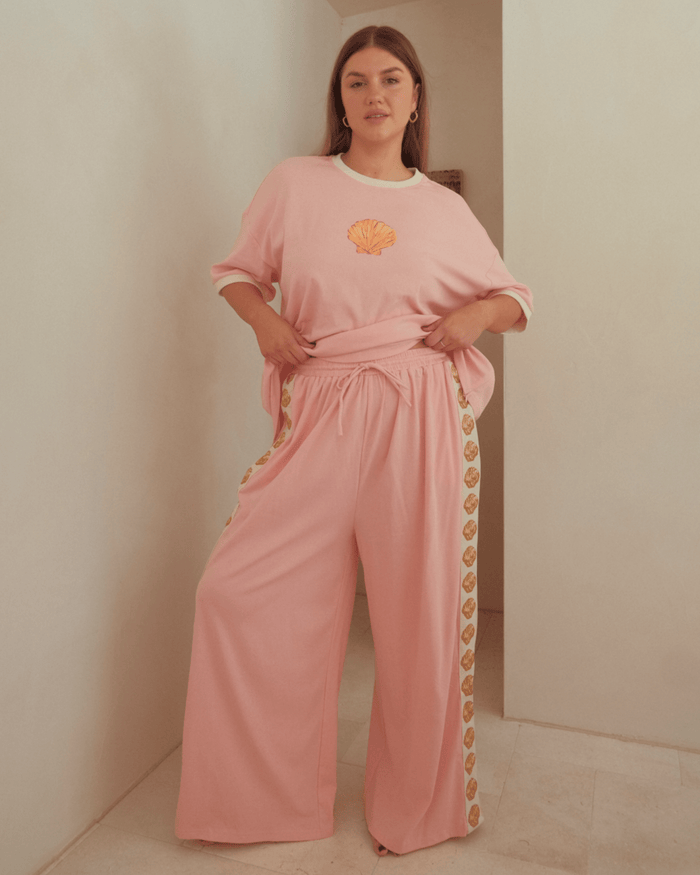 Woman wearing pink matching loungewear set, featuring oversized shirt and high-waisted drawstring pants.