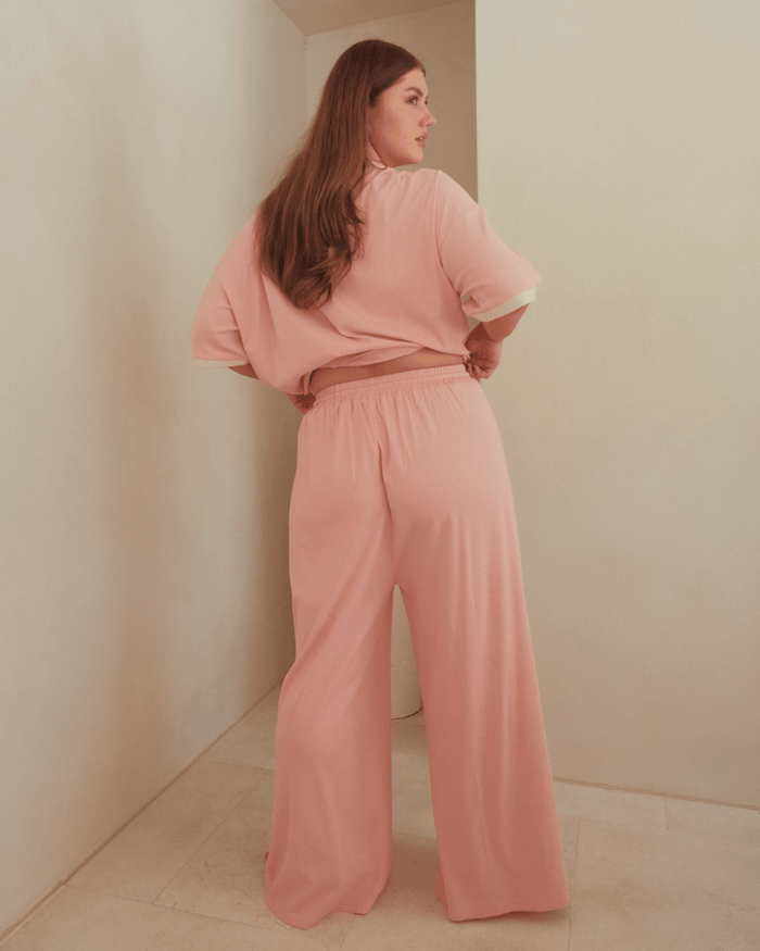 Woman wearing pink relaxed high-waisted lounge pants and oversized shirt.