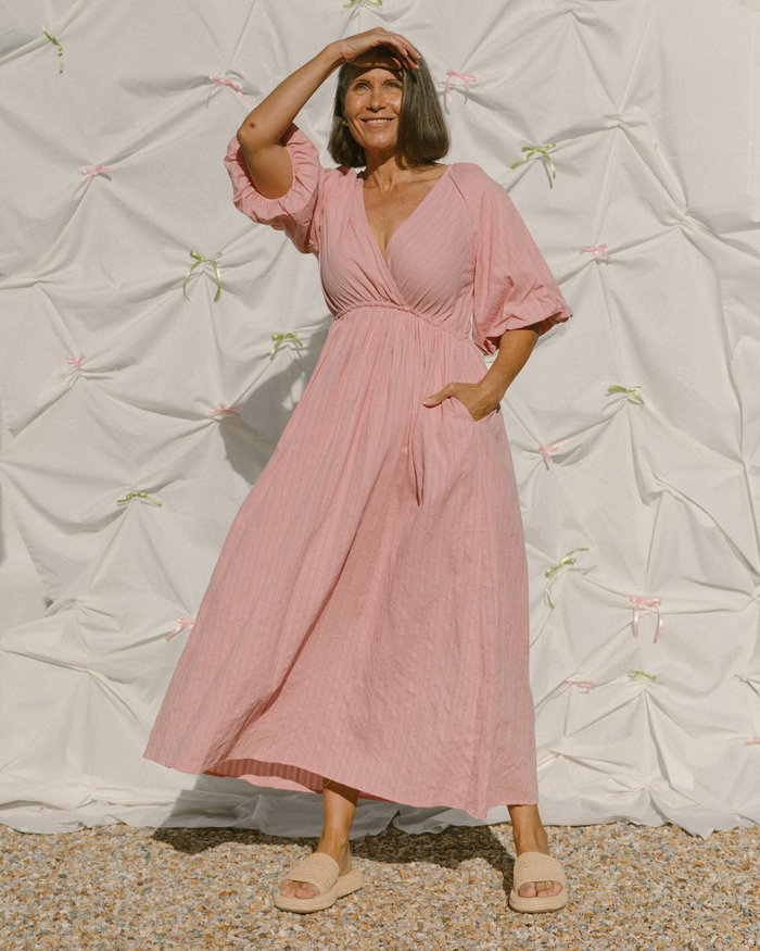 Woman in pink breastfeeding friendly dress that is flowing in the wind.