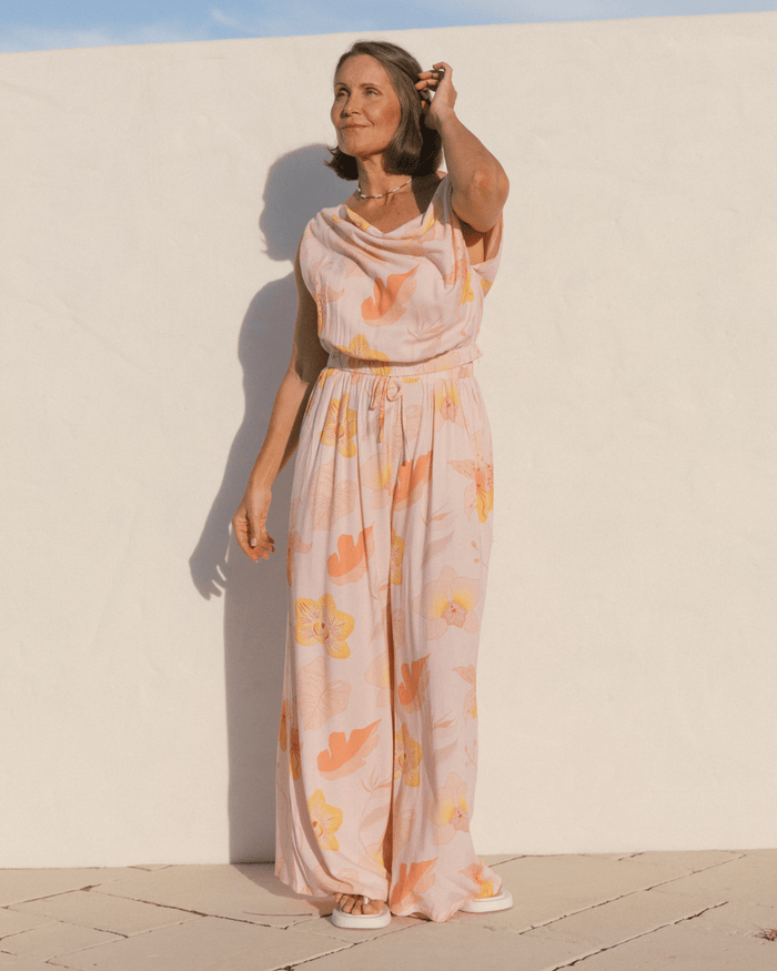 Woman wearing a cowl neck crop top and matching floor length stretchy pants.