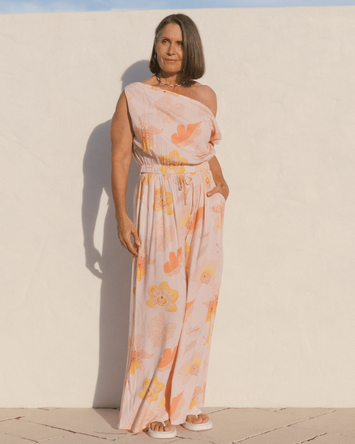 Woman wearing a matching floral set with a off the shoulder crop top and long pants in a breathable fabric.