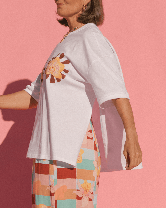 Woman wearing a breastfeeding accessible white graphic oversized tshirt with the side-seam zippers unzipped.