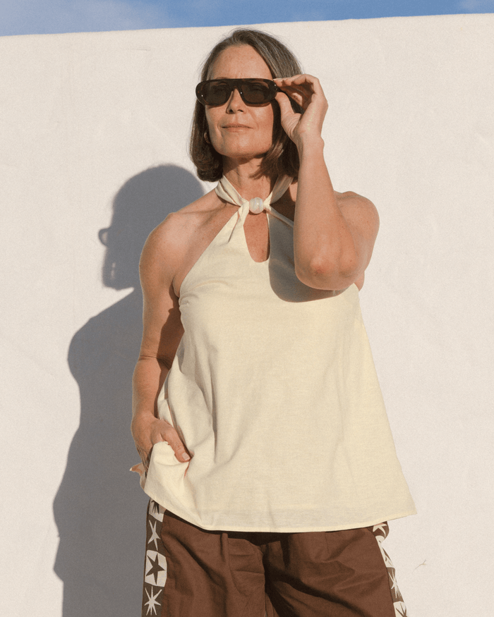 Women wearing stylish pale yellow halter top with a pink bead around the neckline.