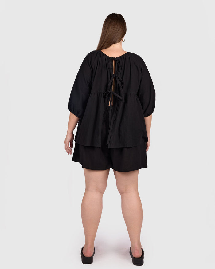 Woman wearing reversible black cotton top with tie up back.