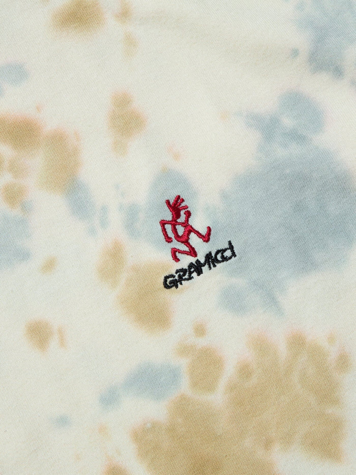 Gramicci X Alpha Cotton Camo Tie Dye Tee by Alpha Industries, beige and light blue tie dye, small red embroidered figure with black Gramicci logo, cotton material.