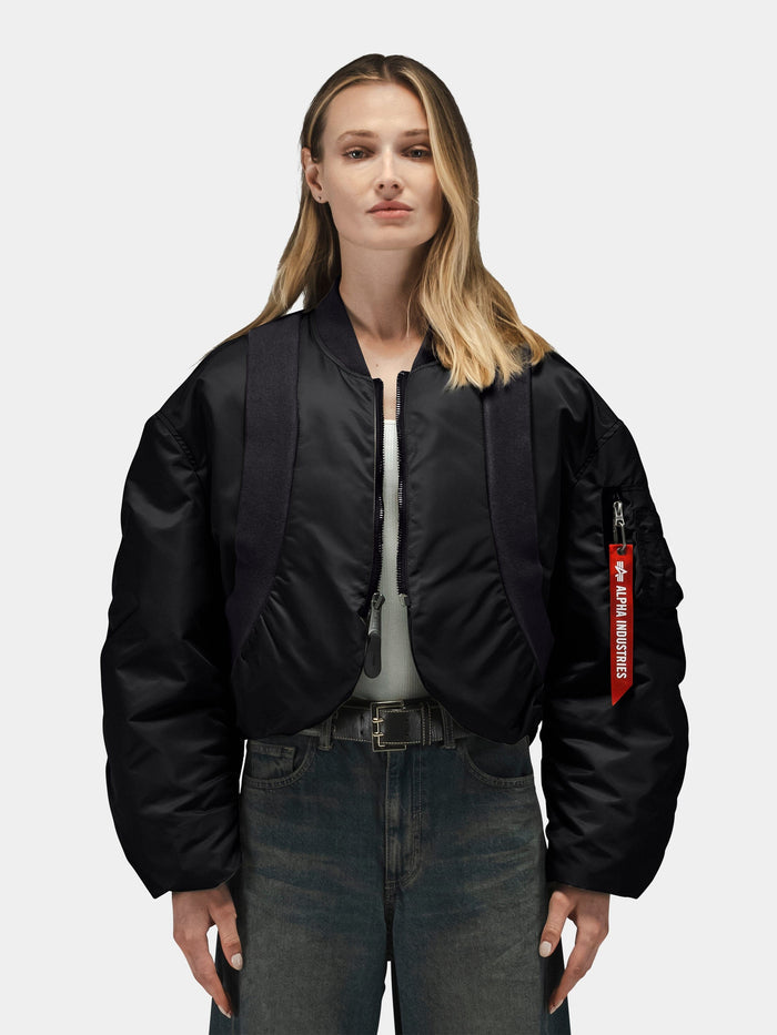 Alpha Industries Knit Rib MA-1 Flight Jacket Womens with red Remove Before Flight tag, gray shirt, and blue jeans.
