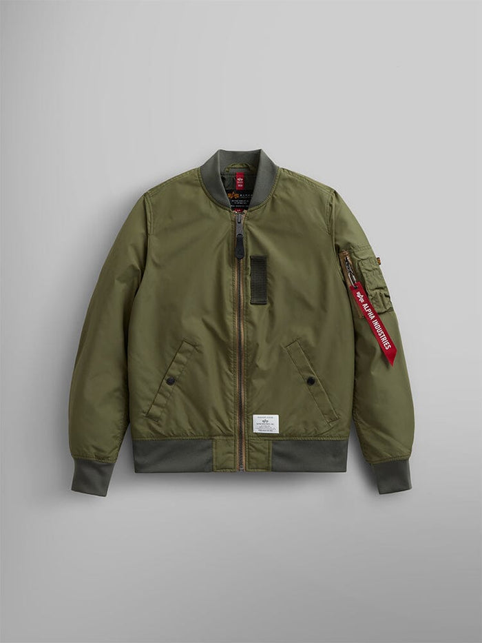 The L-2B Skymaster Gen II Bomber Jacket W by Alpha Industries is designed in OG-107 green and crafted from lightweight, water-resistant nylon. It features ribbed cuffs, hem, and collar, a zippered front closure, side pockets, and includes a stylish red oxygen tab detail on the sleeve.