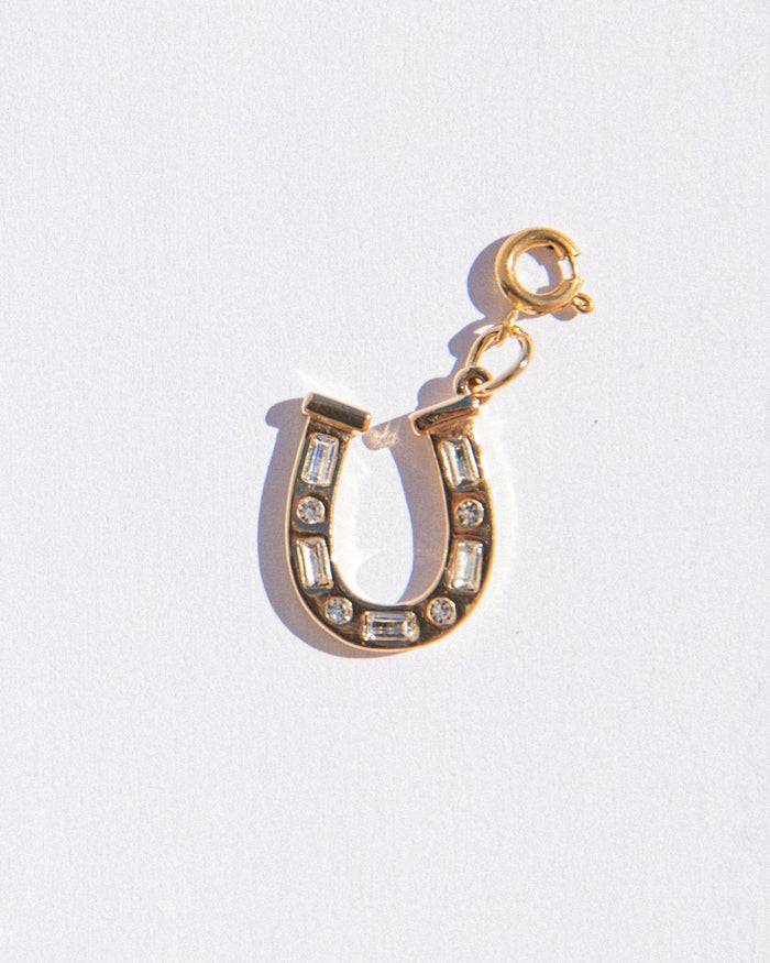 Gold horseshoe charm with crystals on a white background