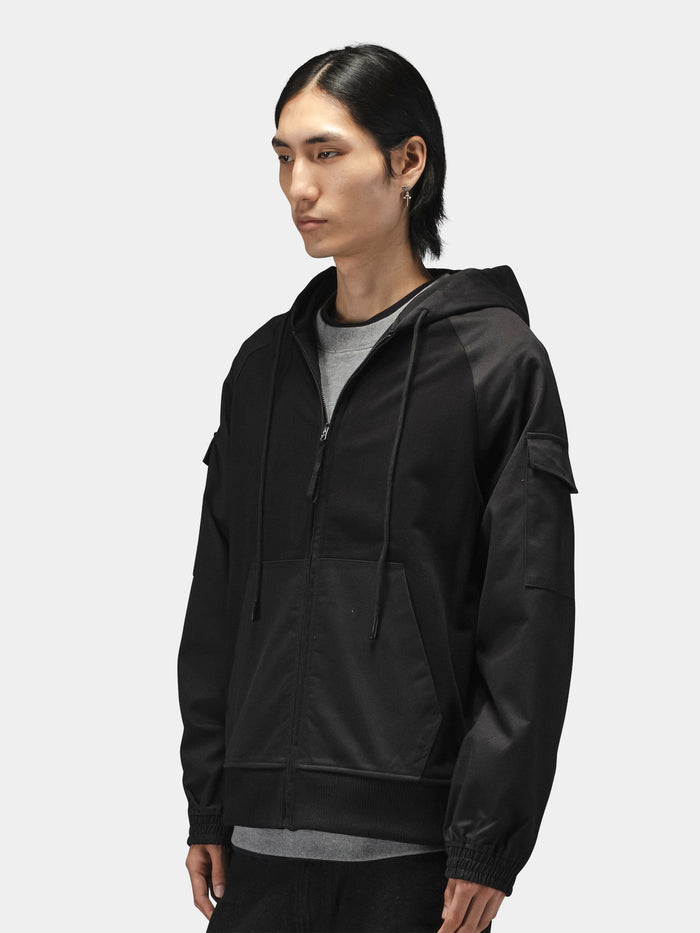 Alpha Industries M-65 Zip Up Hoodie in black over a gray shirt, featuring zip closure and hood.