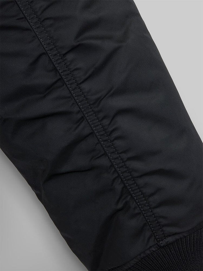 MA-1 Bomber Jacket by Alpha Industries, black padded flight nylon sleeve with visible stitching and ribbed cuff.