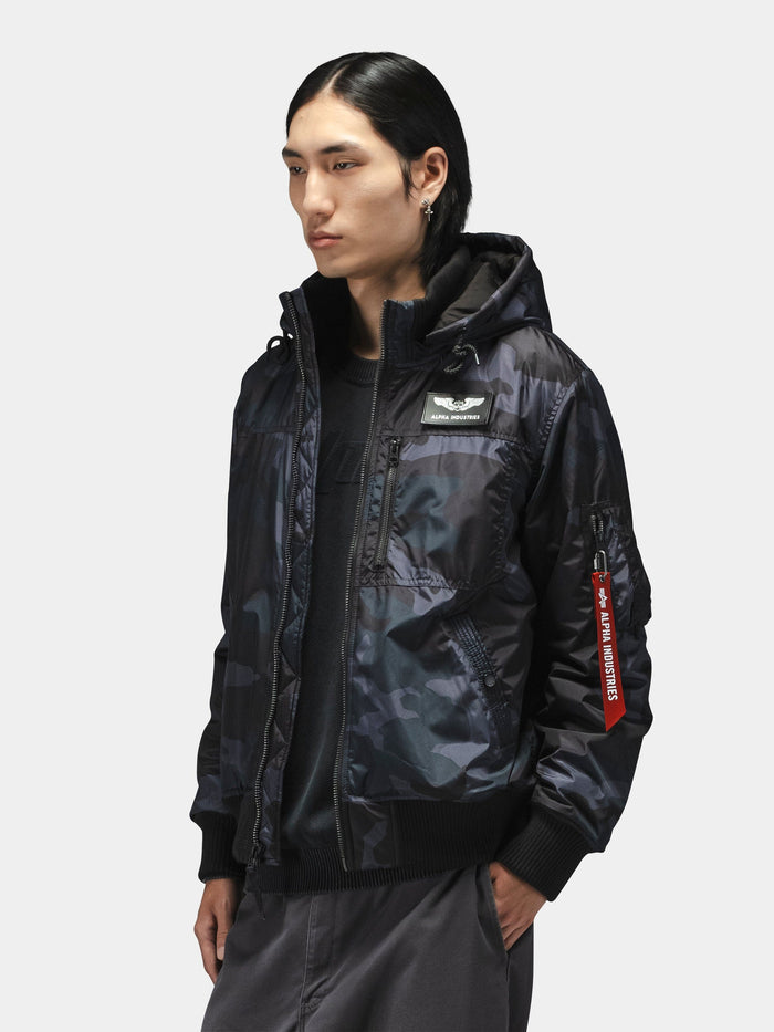 Alpha Industries Hooded Rib Flight Jacket in black with chest patch, red sleeve tag, and utility pocket.