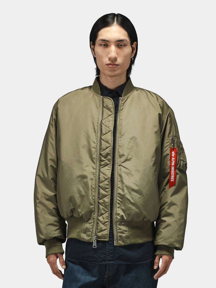 Alpha Industries MA-1 Oxford Flight Jacket in olive green with red "Remove Before Flight" tag on the sleeve.