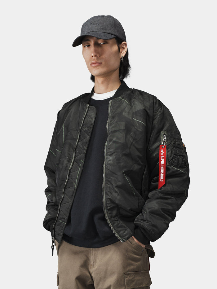 Alpha Industries MA-1 Zippered Print Flight Jacket with red zipper tag, black baseball cap, black shirt, and khaki pants.