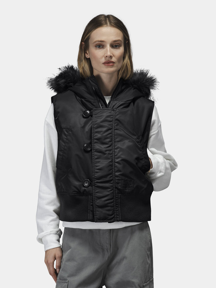 Alpha Industries N-2B Vest Womens in black flight nylon with faux fur hood. Layered over white sweatshirt and gray pants.