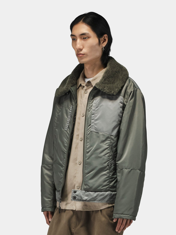 Alpha Industries Nylon Aviator Jacket in gray-green nylon with large faux fur collar, light brown shirt, and khaki pants.