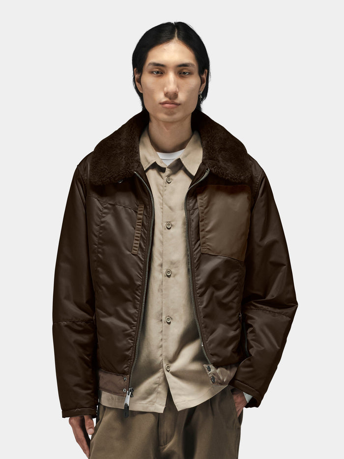 Alpha Industries Nylon Aviator Jacket with dark collar, beige button-up shirt, and khaki pants.