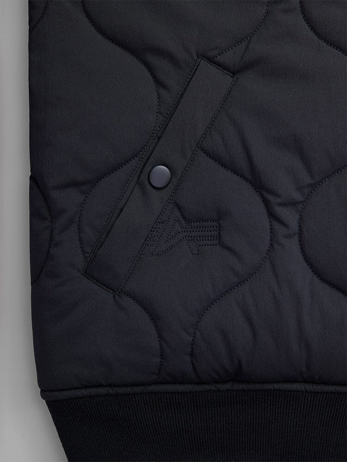 Close-up of the pocket of the Reversible Onion Quilted MA-1 Bomber Jacket in black by Alpha Industries, featuring a buttoned pocket and textured quilted pattern, made from water-resistant nylon.