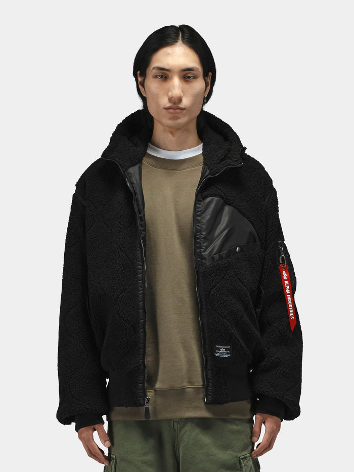 Alpha Industries Sherpa Onion Quilting Flight Jacket in black with brown shirt and green pants, featuring quilted design.