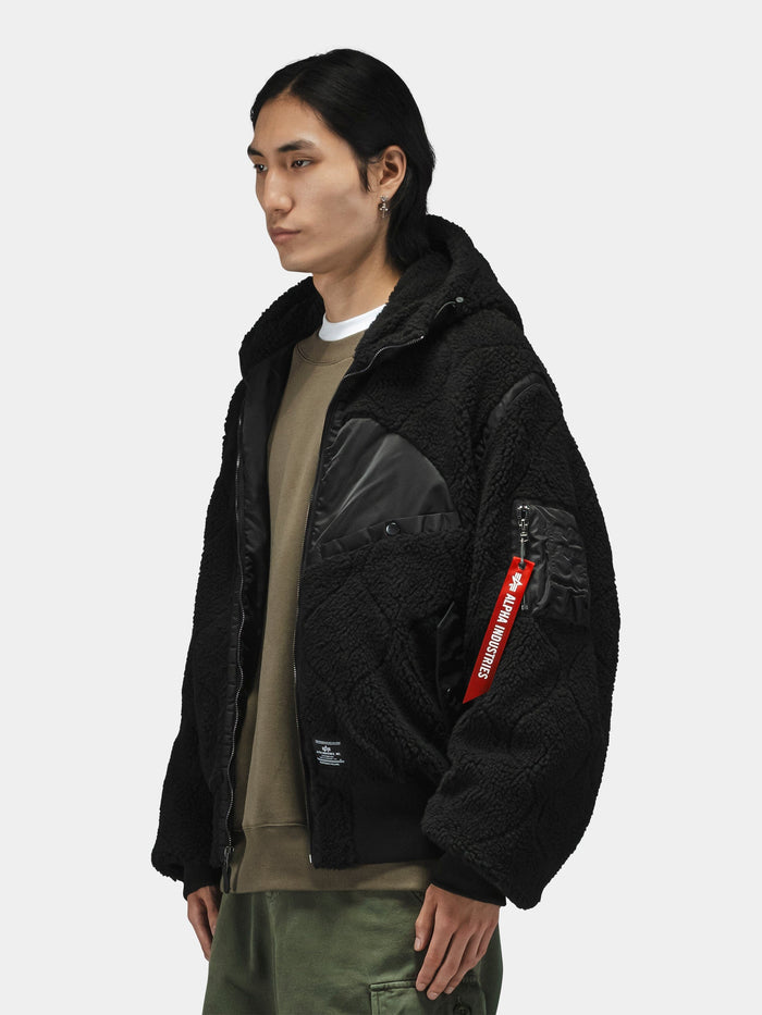 Alpha Industries Sherpa Onion Quilting Flight Jacket with utility sleeve pocket, red tag, olive sweatshirt, and green pants.