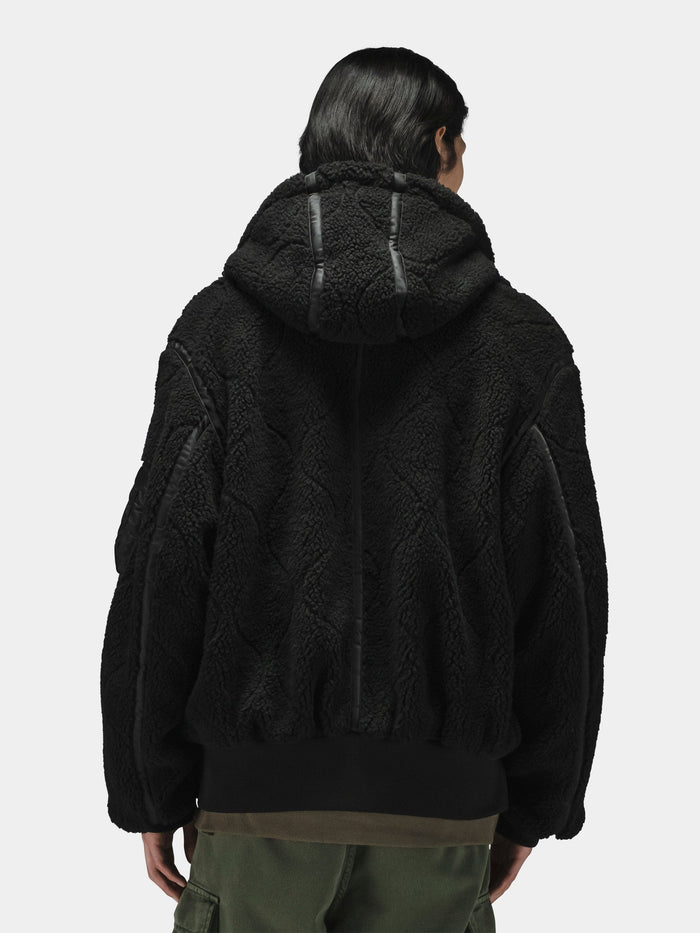 Alpha Industries Sherpa Onion Quilting Flight Jacket in black with black trim, paired with olive green pants.