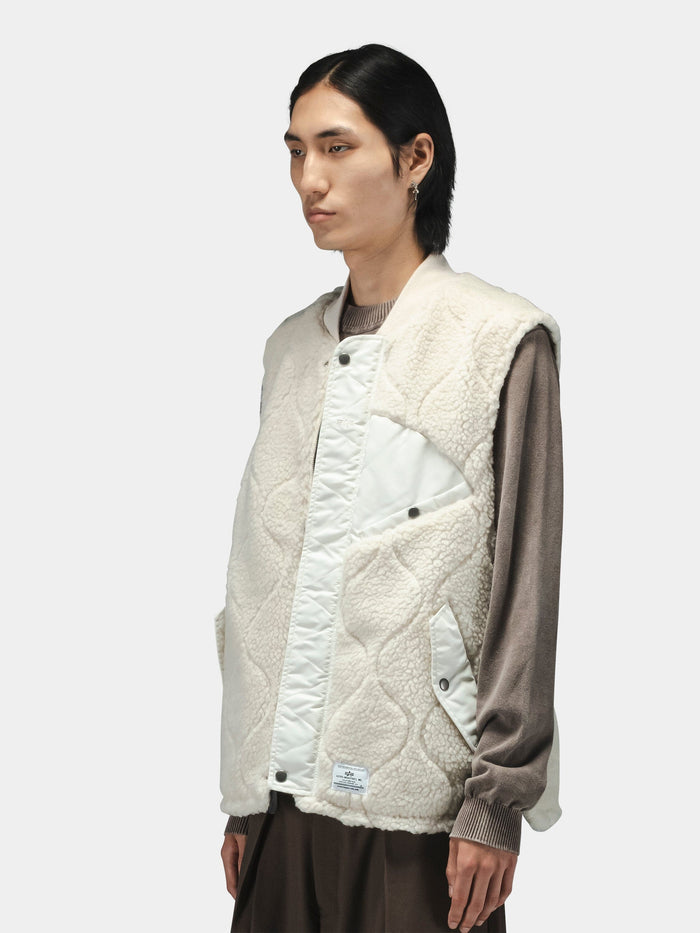 Alpha Industries Sherpa Onion Quilting Vest in cream, quilted design, sherpa material, worn over brown long-sleeve shirt and pants.