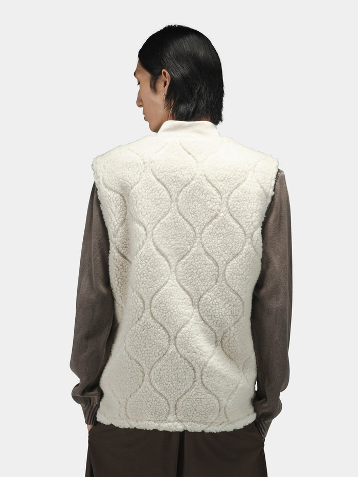 Alpha Industries Sherpa Onion Quilting Vest, sleeveless, white, layered over a long-sleeved brown shirt.