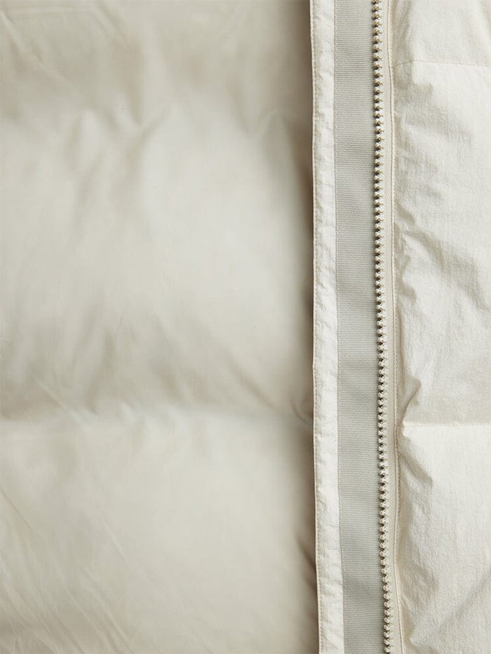 Close-up of the Sierra Short Puffer W by Alpha Industries, showcasing its light-colored quilted fabric with down fill, unzipped zipper, and water-resistant design.