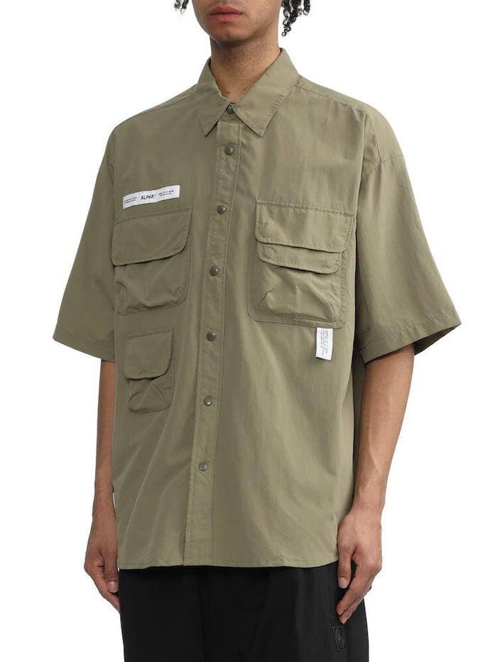 UNFRM Nylon Utility Shirt by Alpha Industries, olive green short sleeve button-up with silicone Alpha print and multiple patch pockets.