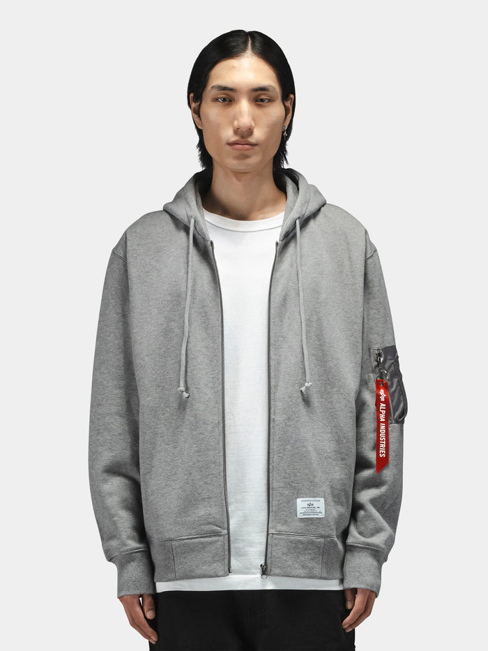 Alpha Industries Utility Pocket Full Zip Up hoodie in grey with a red Remove Before Flight tag on the sleeve.