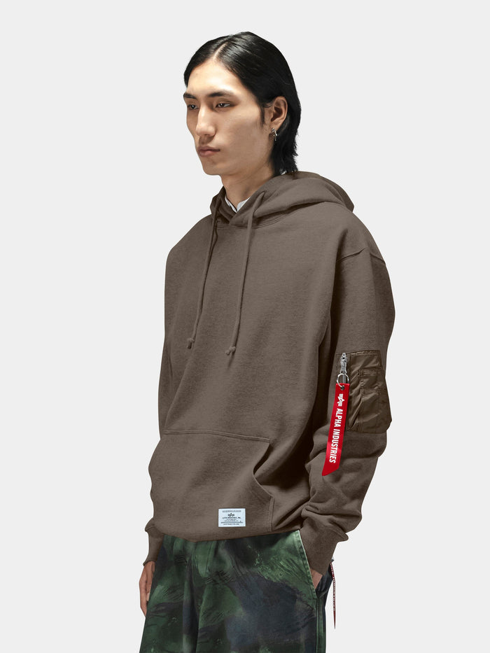 Alpha Industries Utility Pocket Hoodie with MA-1 utility sleeve pocket and red Remove Before Flight tag, green camo pants.